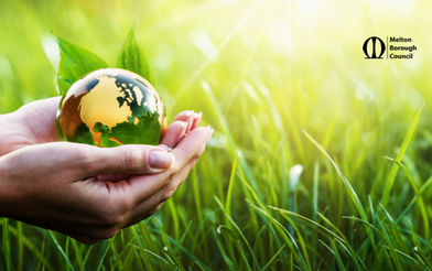 Person holding the Earth in their hands near grass